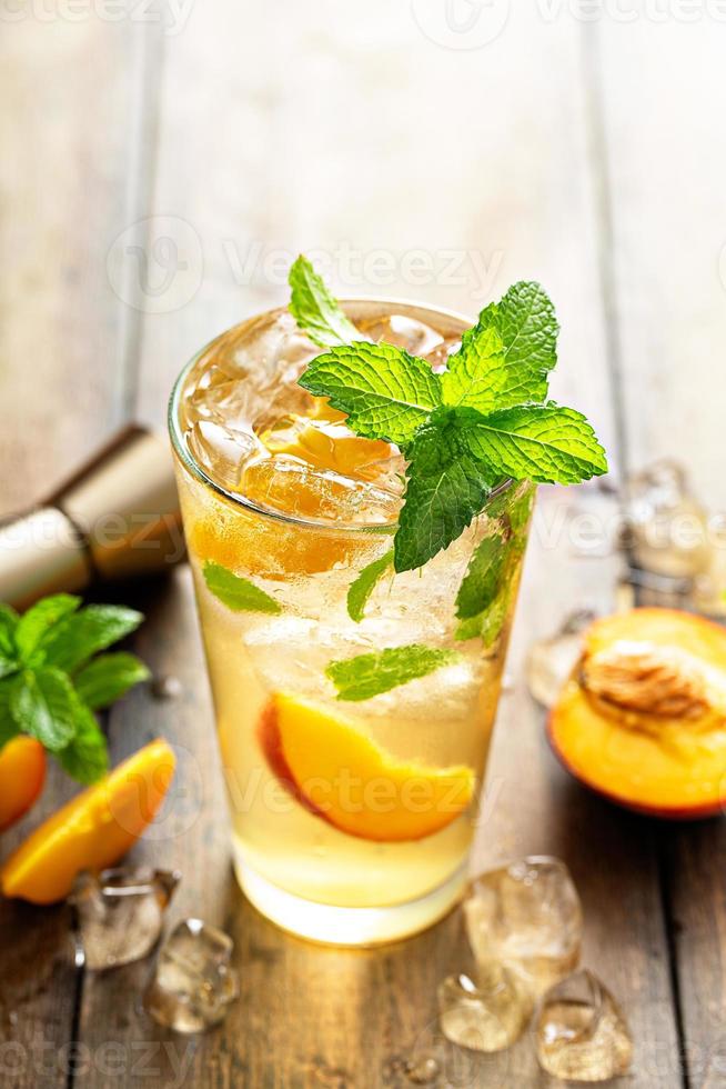 coquetel de mojito de pêssego de verão com fatias de menta fresca, limão e pêssego foto