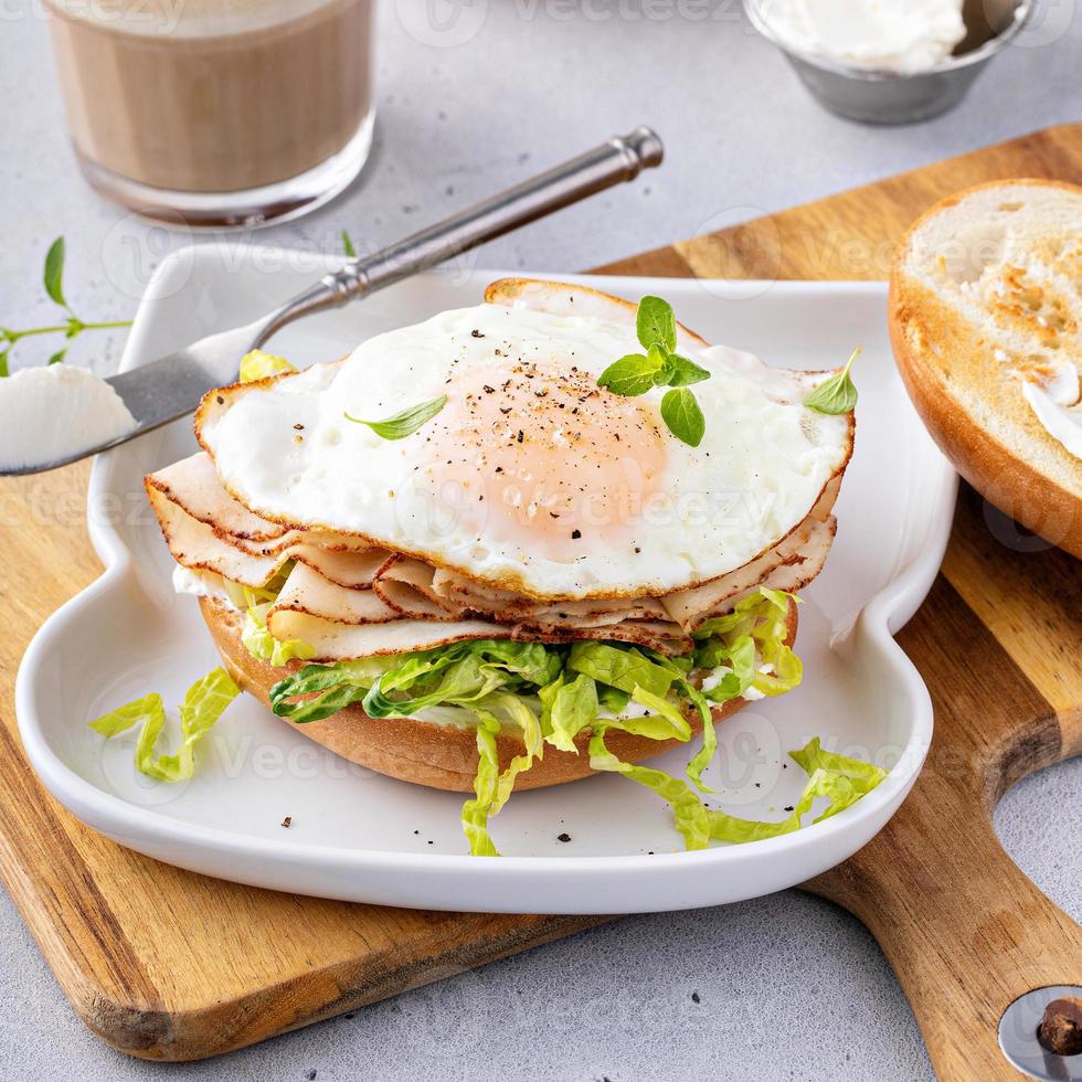 sanduíche de café da manhã com bagel de peru com alface e ovo frito foto