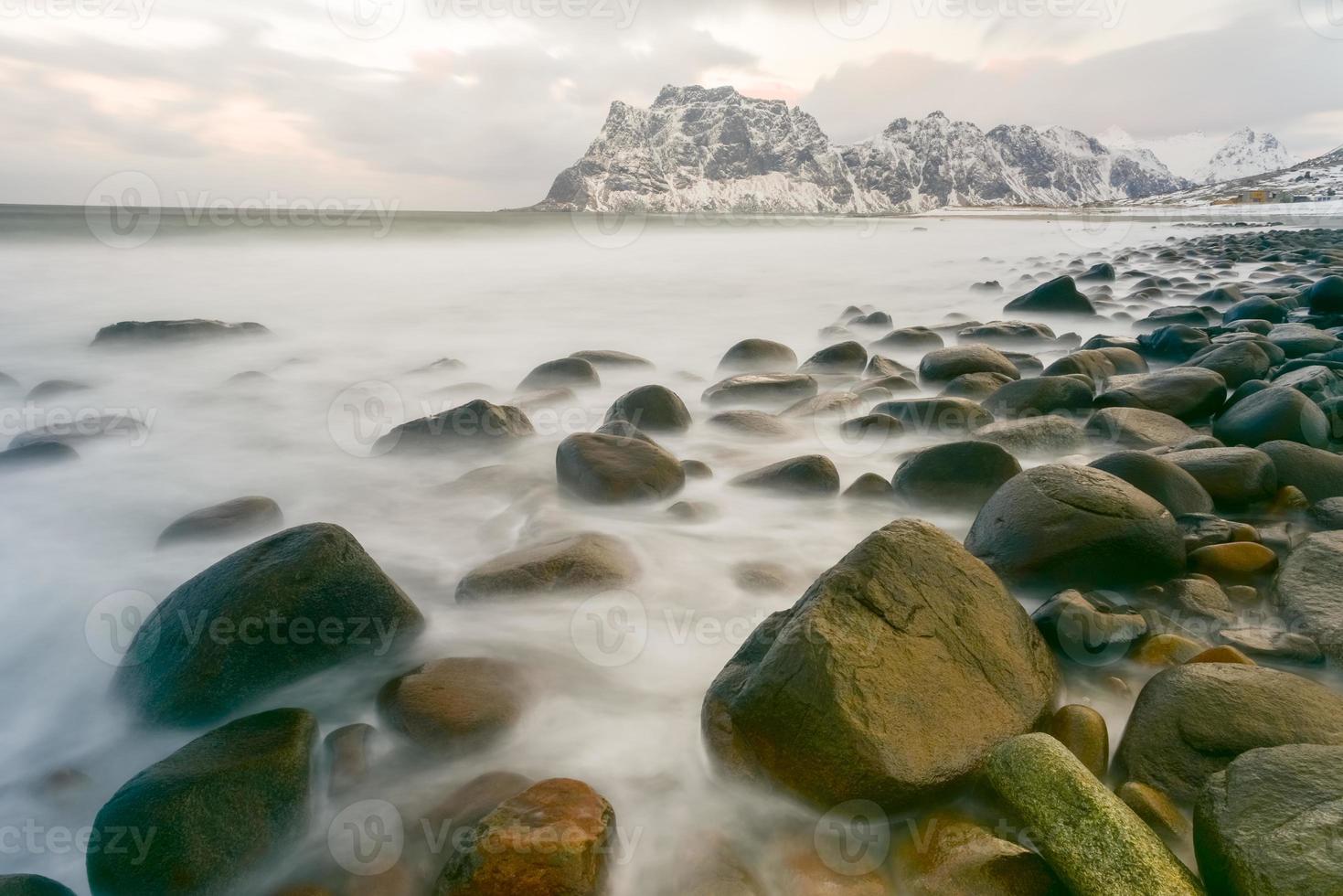 ondas fluindo sobre a praia de utakleiv, ilhas lofoten, noruega no inverno. foto