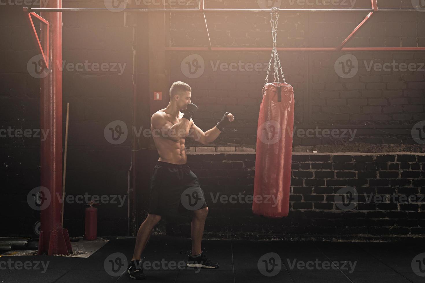 jovem lutador de mma forte e saco de pancadas vermelho foto