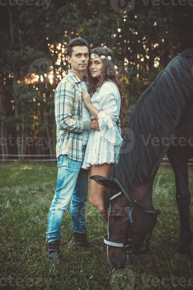 jovem casal abraçado no prado com cavalos foto