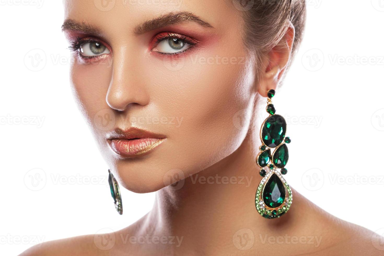 mulher bonita com uma maquiagem colorida está usando brincos com esmeraldas verdes foto