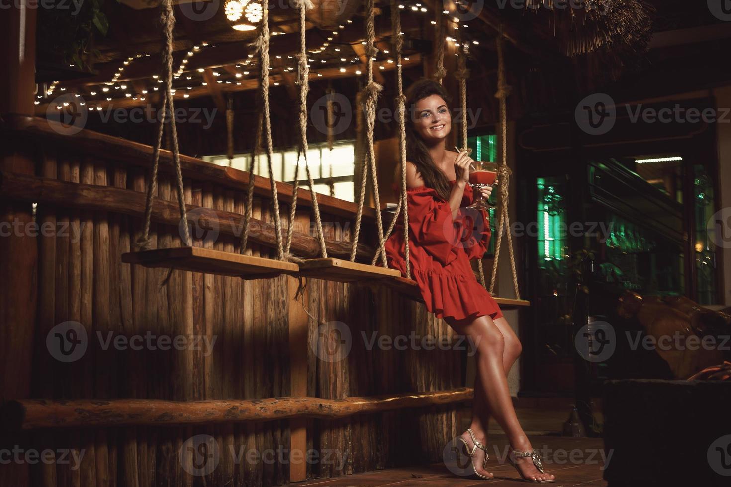 mulher encantadora usando vestido vermelho no bar de verão à noite foto