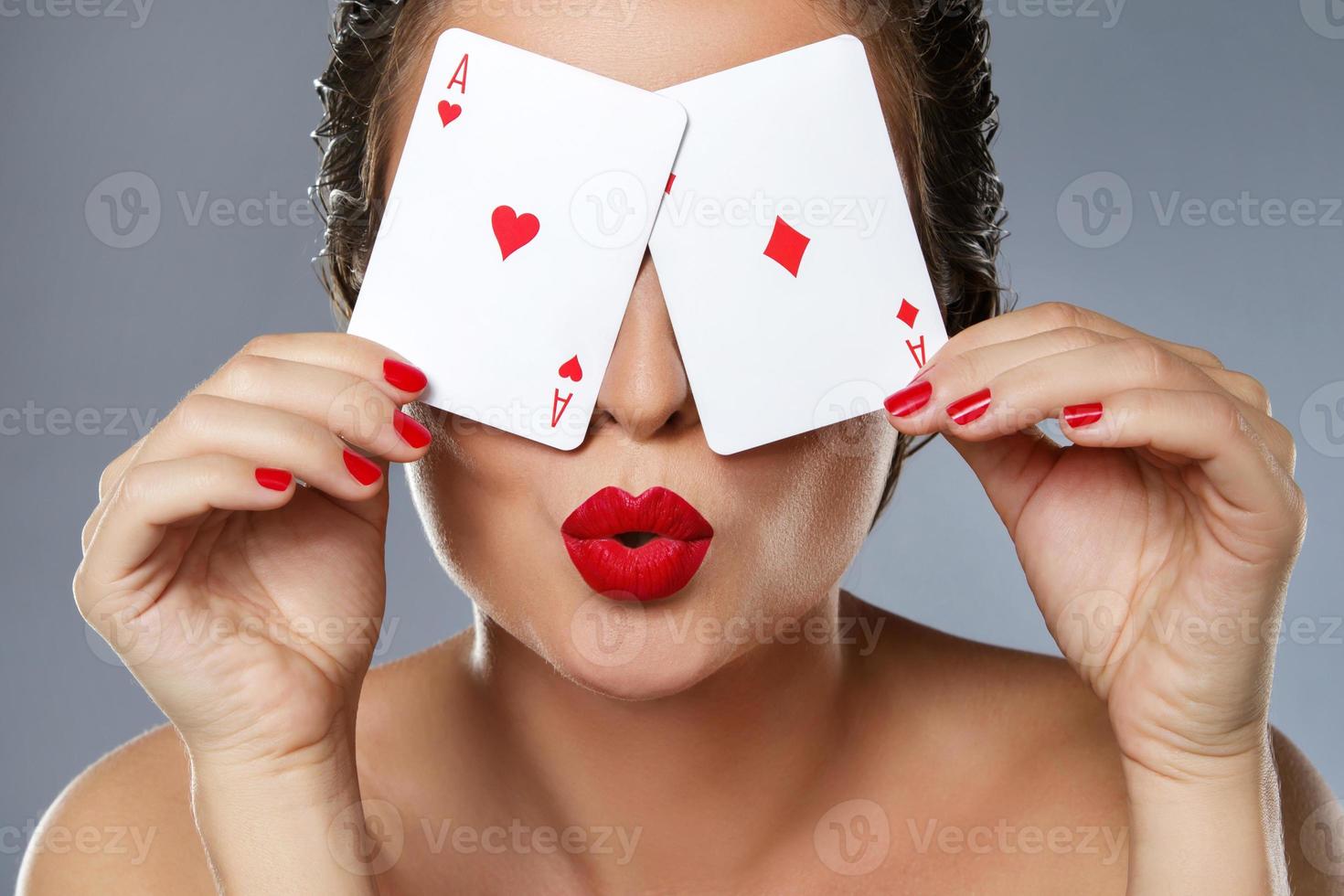 mulher com lábios vermelhos está segurando dois ases nas mãos foto
