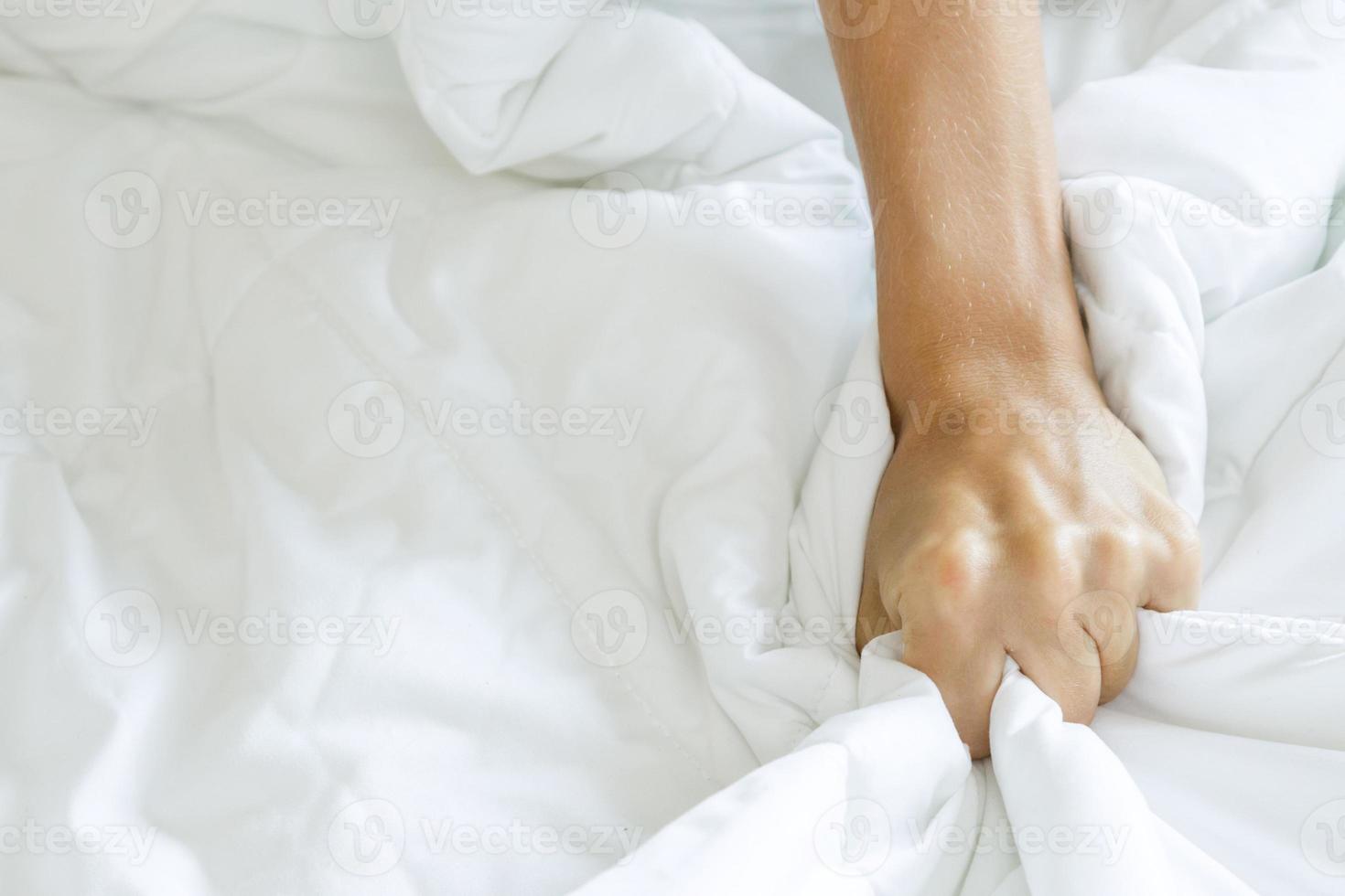 forte mão feminina apertando o lençol no quarto foto