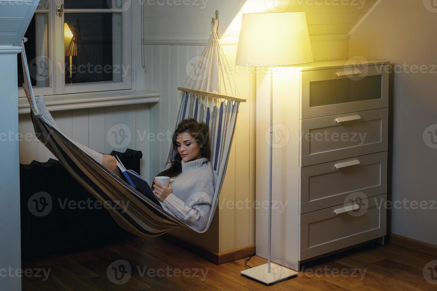 mulher deitada na rede e lendo livro foto