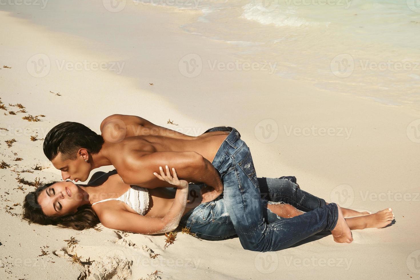 lindo casal vestindo jeans na praia tropical foto