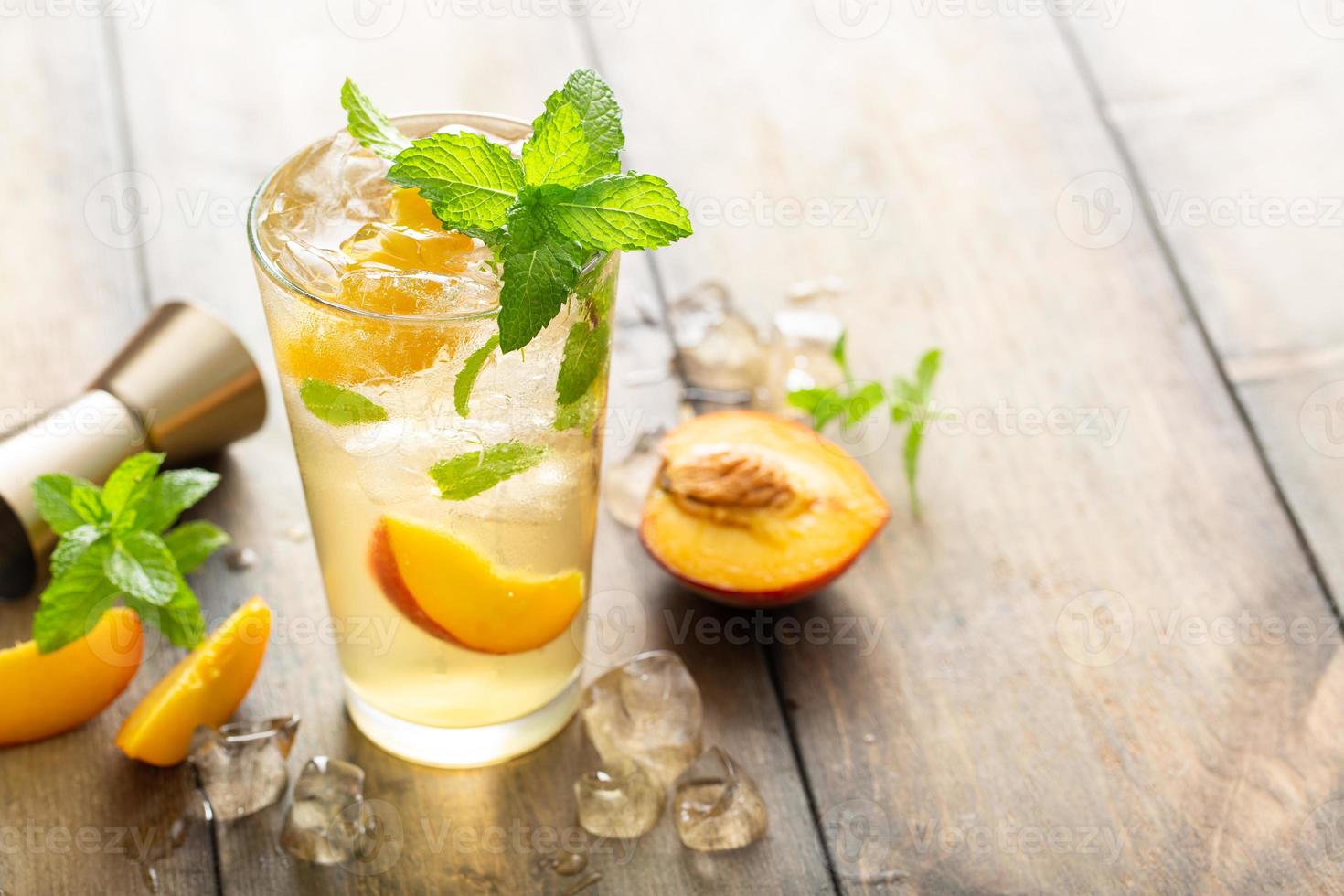 coquetel de mojito de pêssego de verão com fatias de menta fresca, limão e pêssego foto