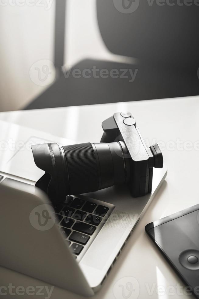 local de trabalho do fotógrafo com uma câmera mirrorless, laptop e mesa digitalizadora foto