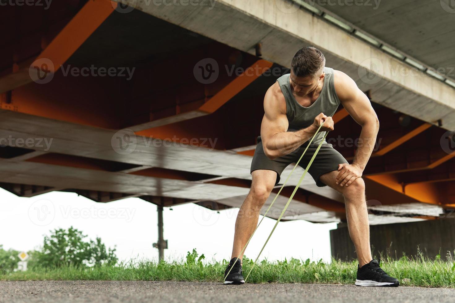 homem musculoso durante treino com elásticos de resistência em uma rua foto
