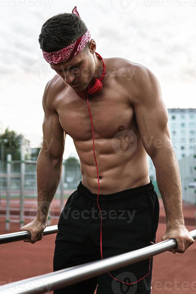 homem musculoso vestindo bandana vermelha durante seu treino de ginástica na rua foto