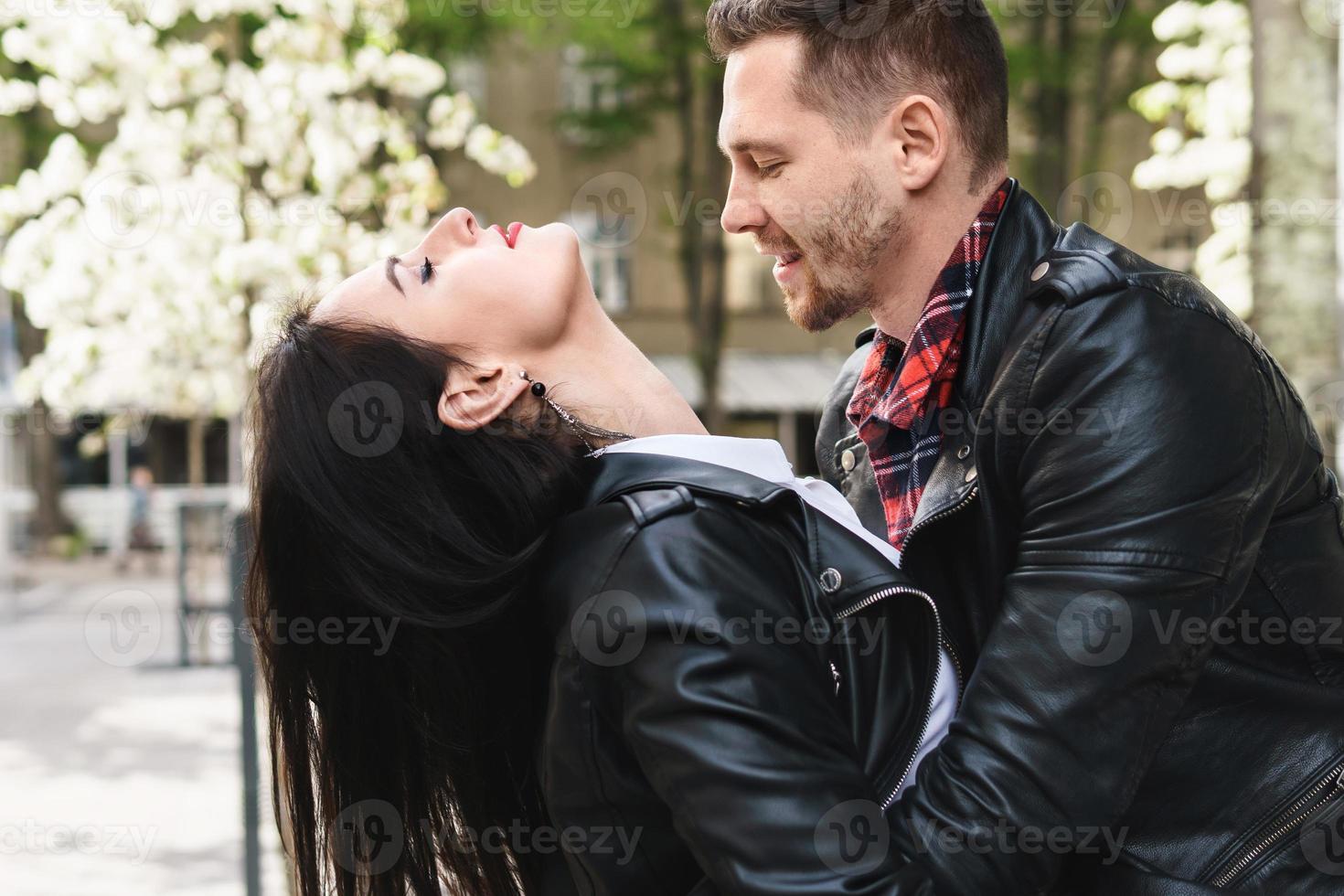 lindo casal apaixonado vestindo jaquetas de couro durante um encontro em uma rua da cidade foto