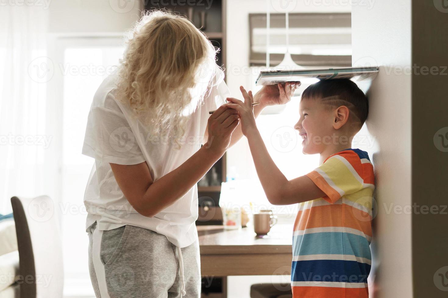 mãe brincando medindo a altura de seu filho foto