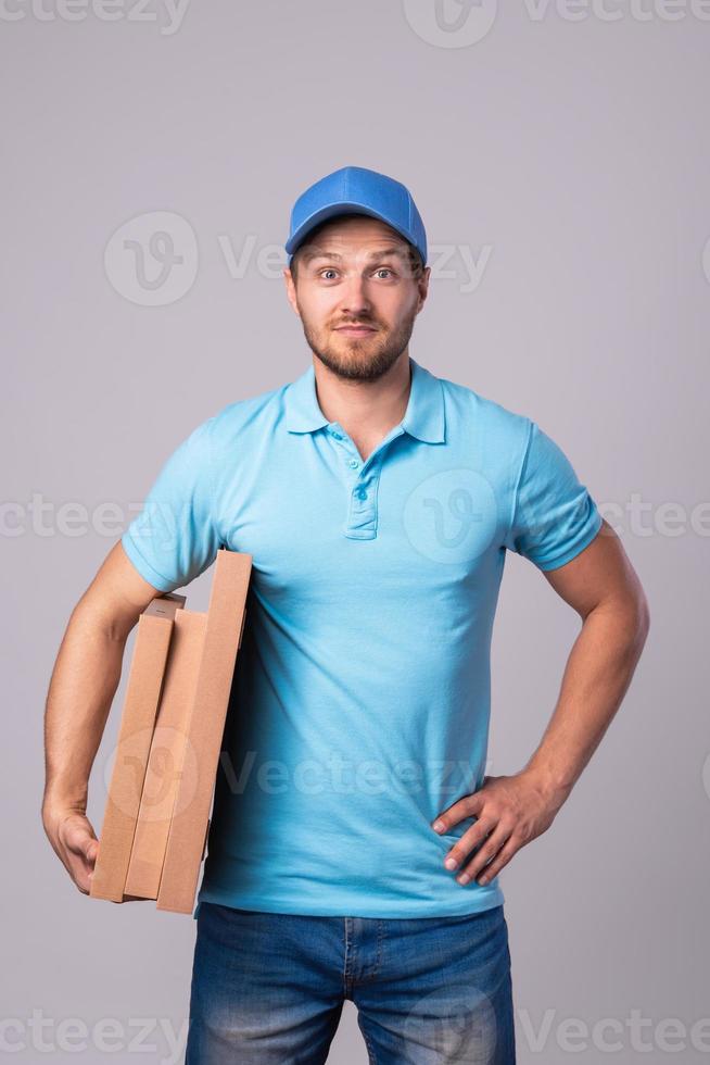 jovem entregador está segurando caixas com uma deliciosa pizza foto
