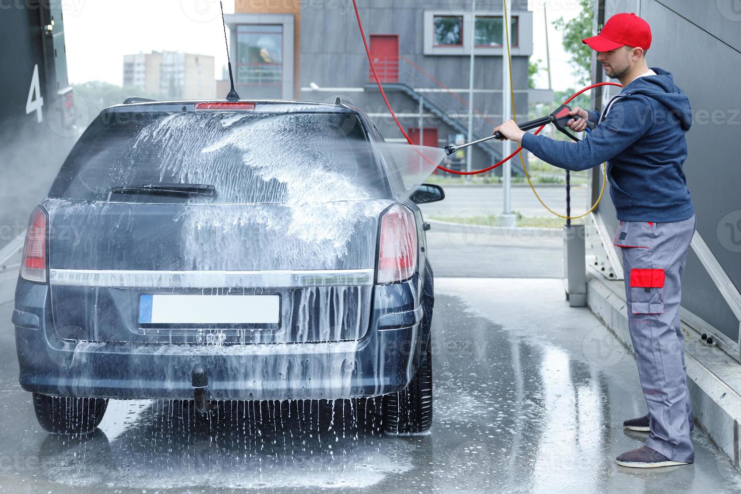 trabalhador de lavagem de carros está lavando o carro do cliente foto