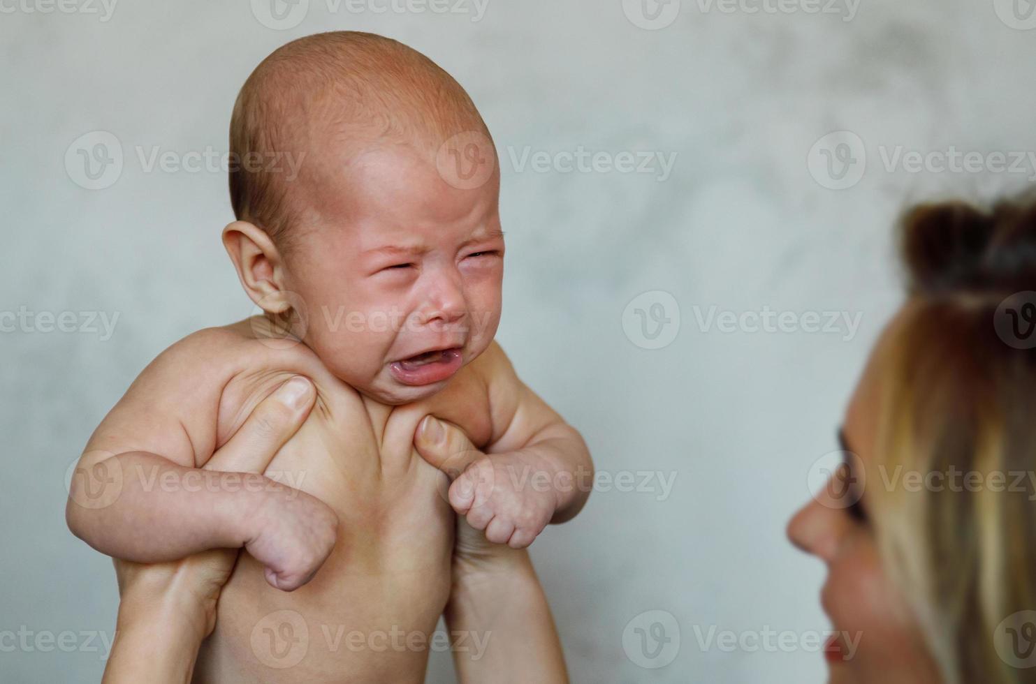 bebê infantil chorando nas mãos da mãe foto