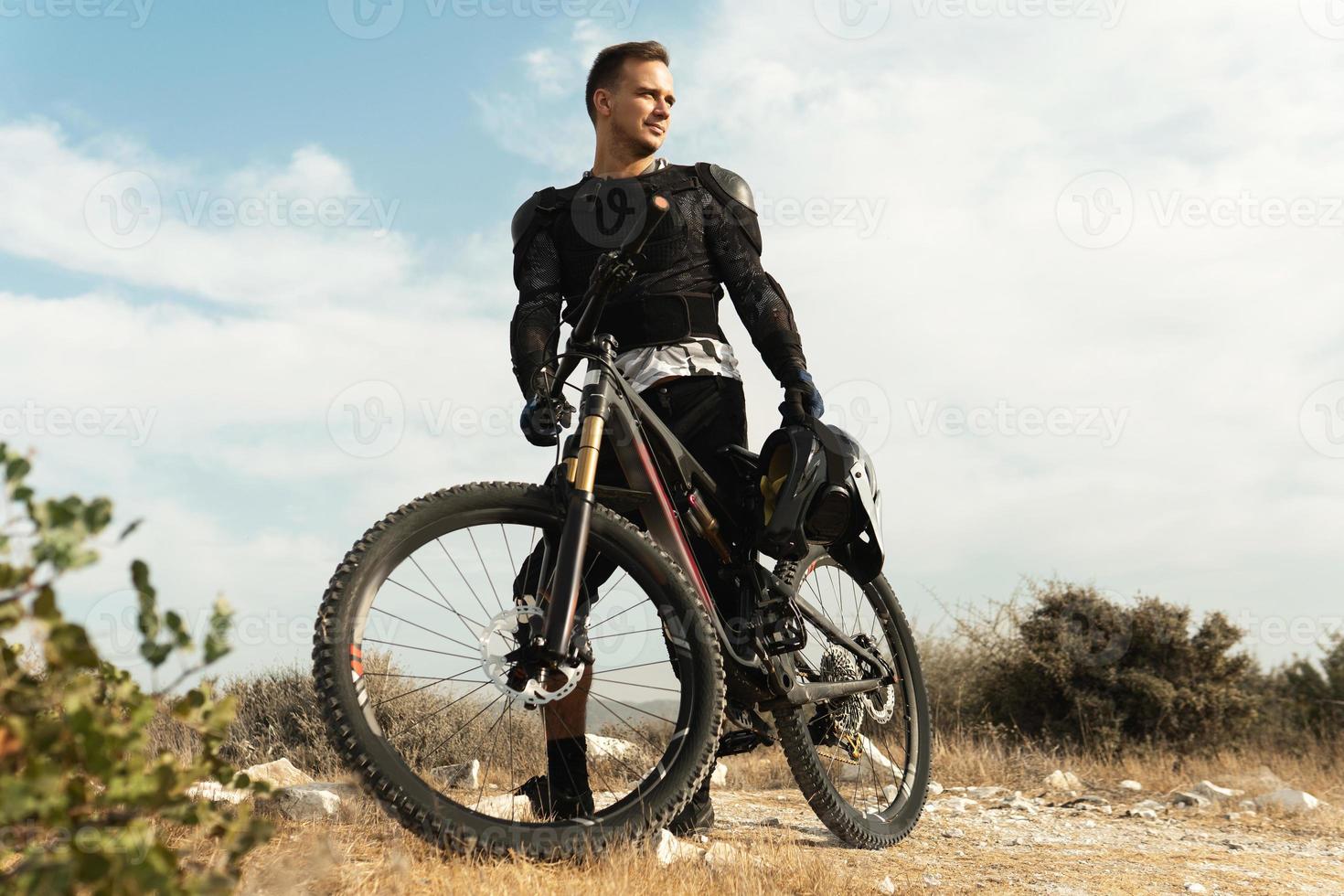 piloto de downhill totalmente equipado com equipamento de proteção e sua bicicleta foto