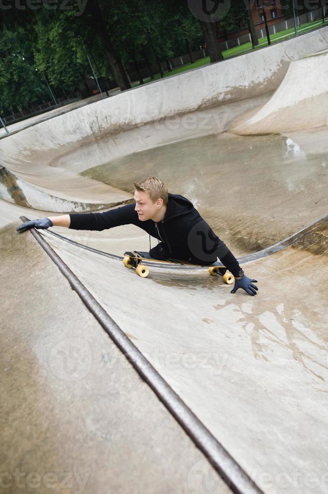 cara deficiente motivado com um longboard no skatepark foto