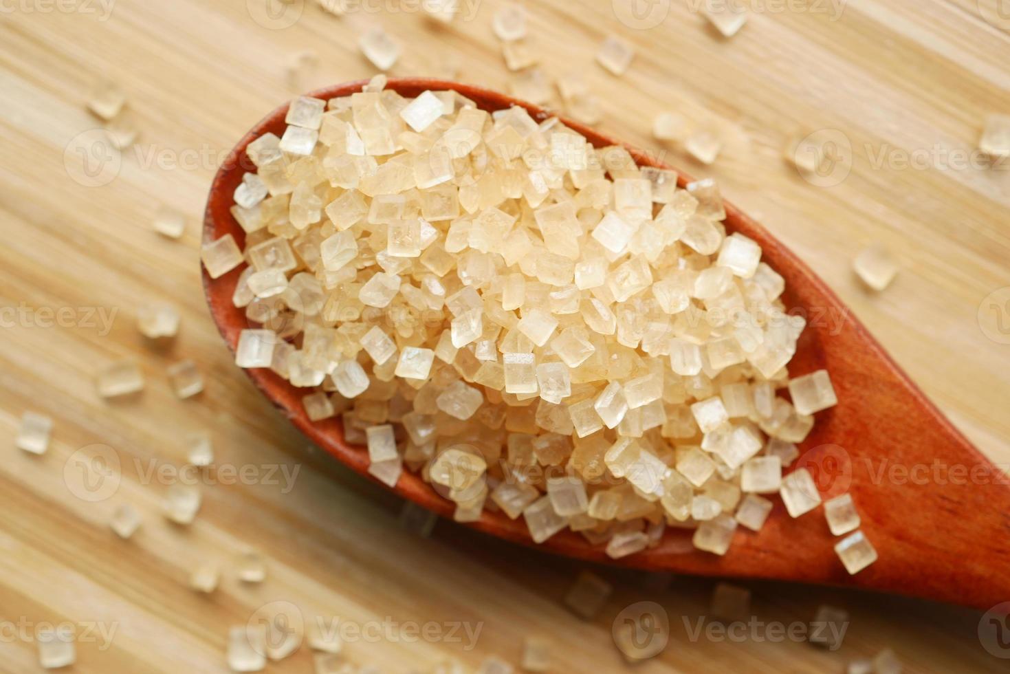 cristal de açúcar mascavo em uma colher de pau na mesa foto