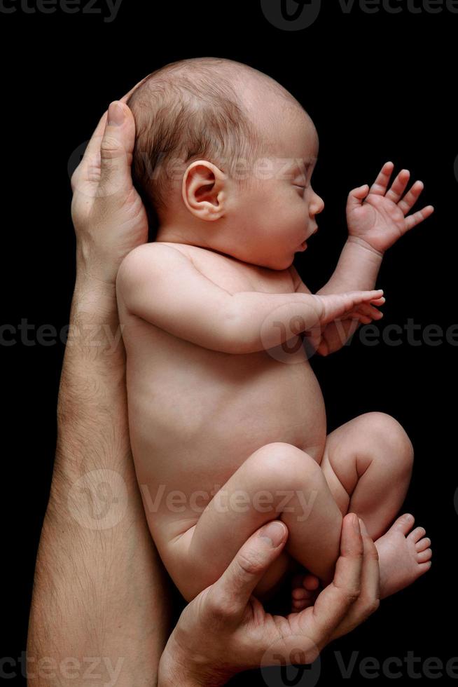 lindo bebê recém-nascido deitado nas mãos do pai foto