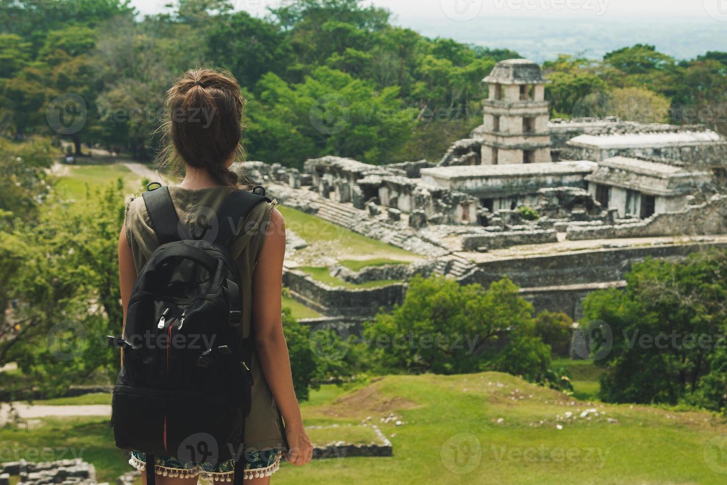 mulher com uma mochila ao lado de antigas ruínas maias foto