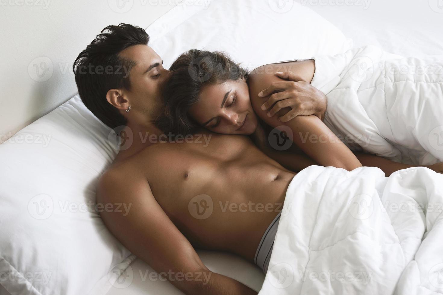 jovem casal lindo está deitado na cama de manhã foto