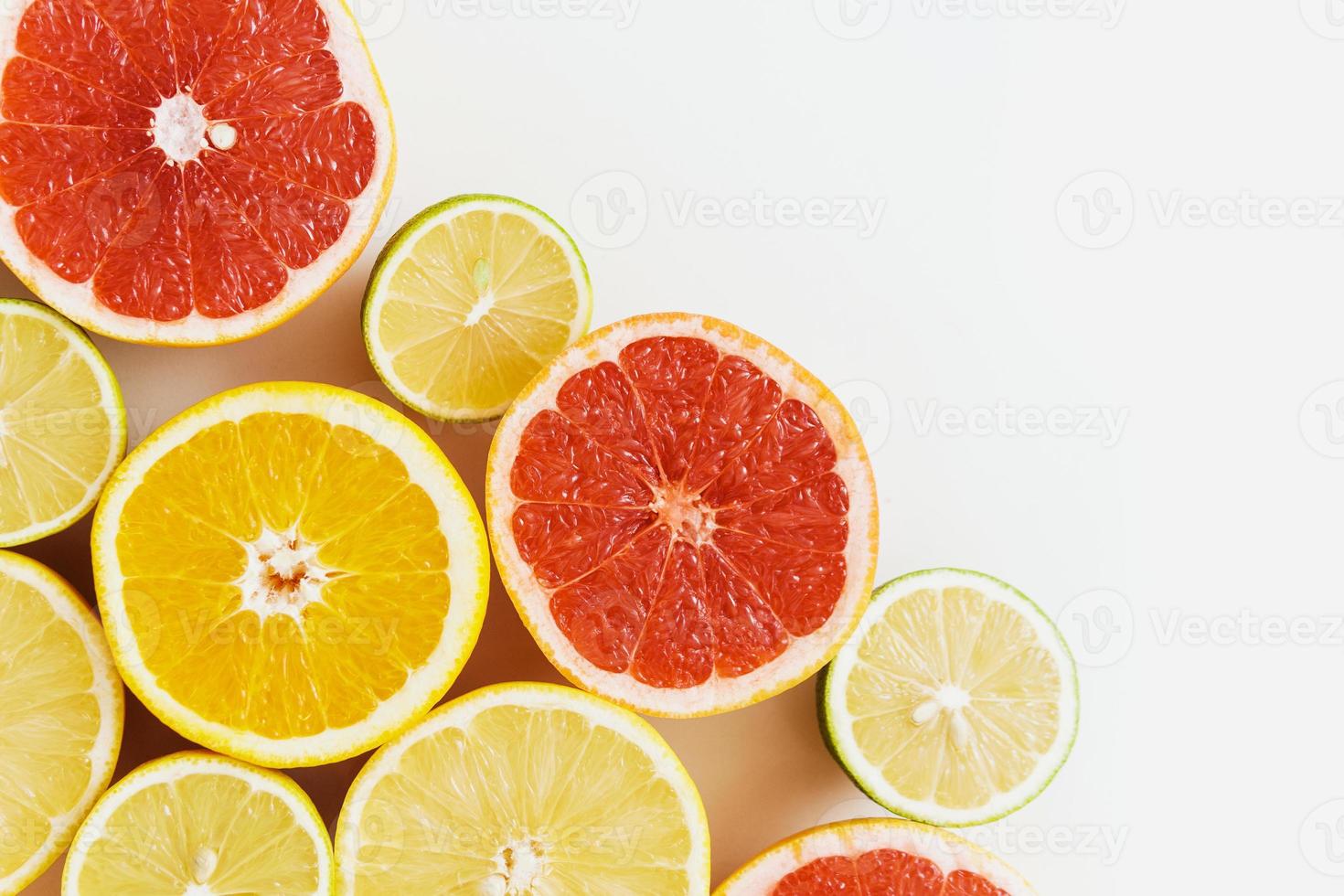 frutas cítricas fatiadas, como toranja, laranja, limão e limão em fundo branco foto