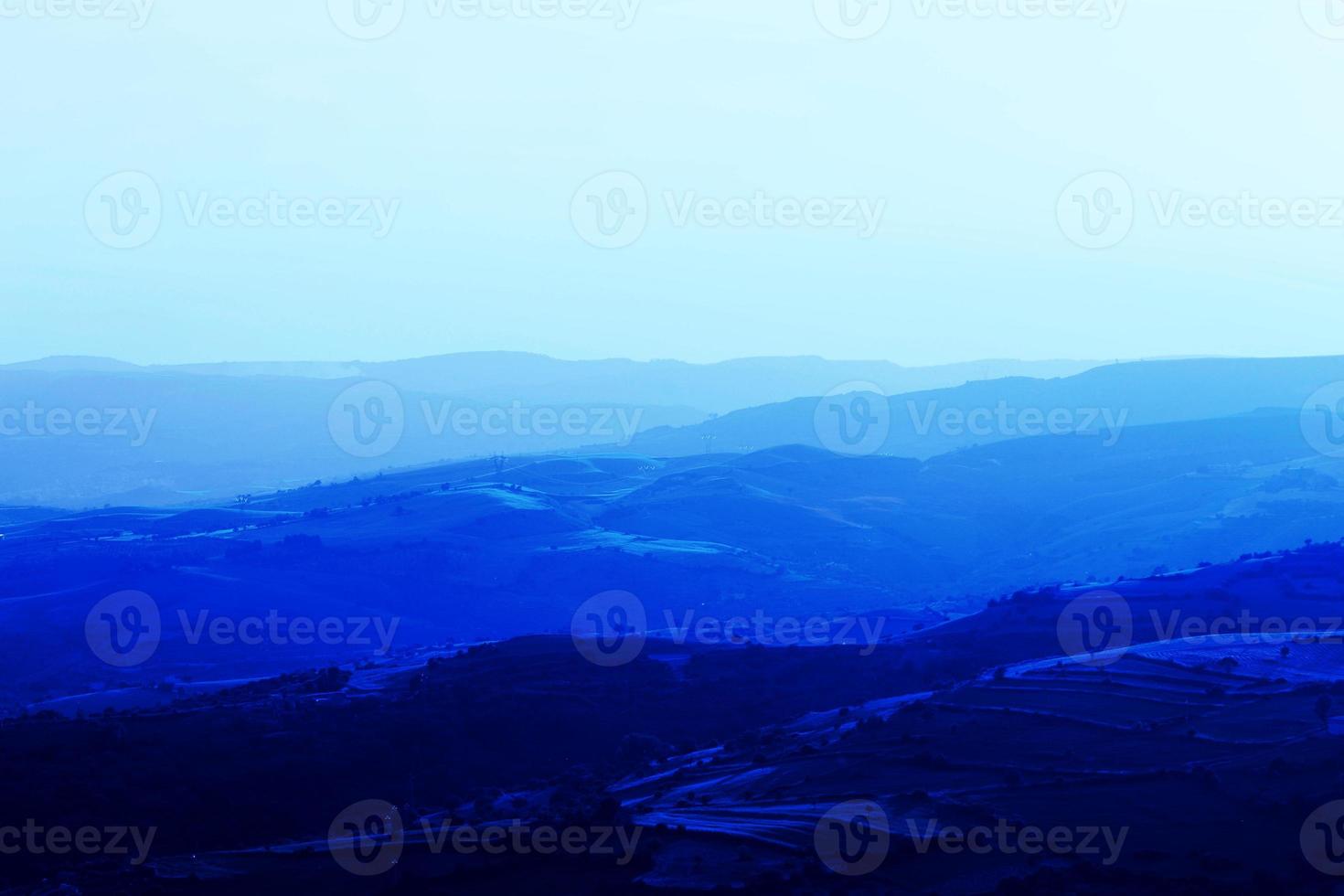 camadas de cadeias de montanhas empilhadas em silhueta azul. perspectiva aérea de colinas azuis. foto