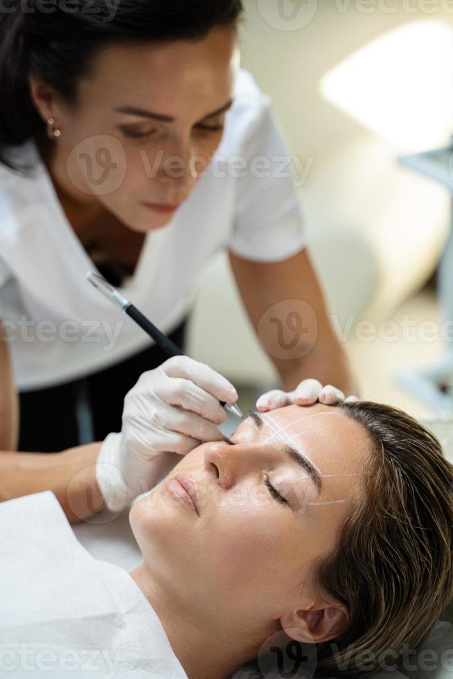 mulher durante procedimento profissional de mapeamento de sobrancelha foto