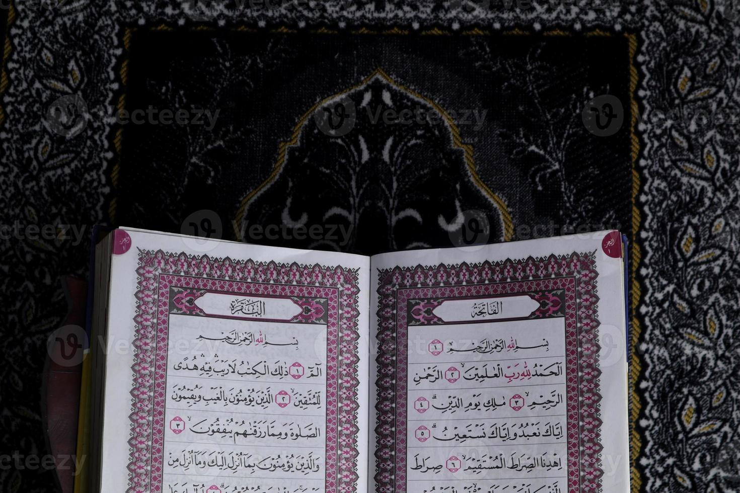 al-quran que está acima do tapete de oração com fundo preto foto
