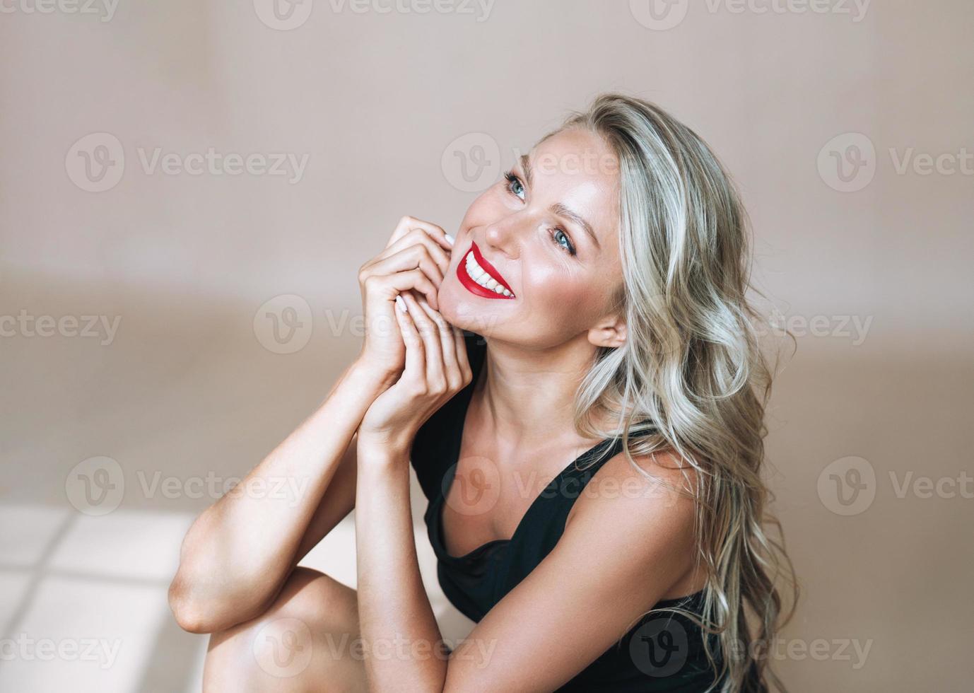 retrato de linda jovem loira feliz com maquiagem brilhante em vestido de noite em fundo bege foto