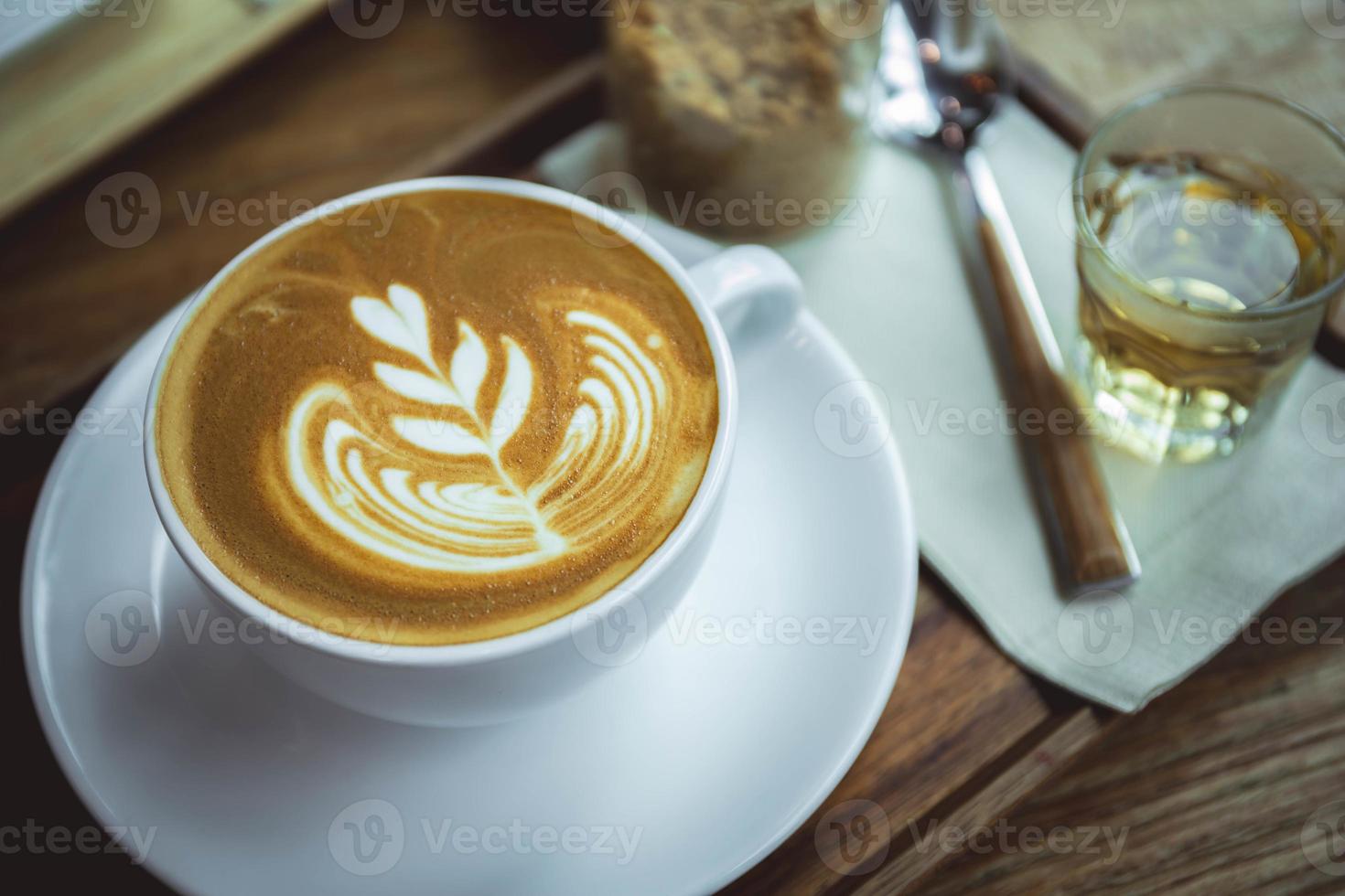 xícara de café com leite com aroma no estilo de café de mesa de madeira foto