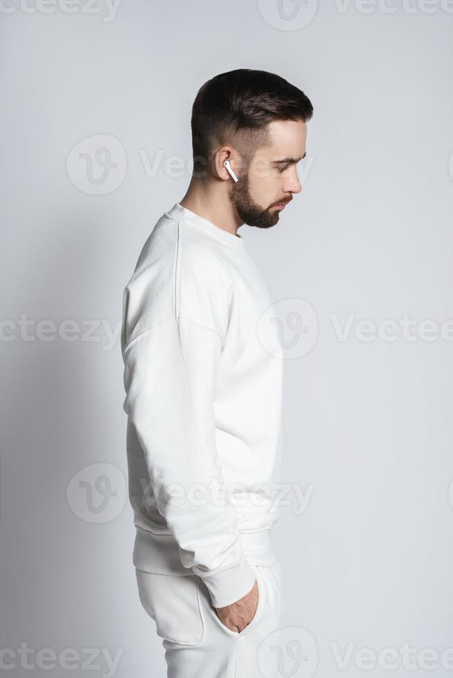 homem bonito vestindo moletom branco com fones de ouvido sem fio foto