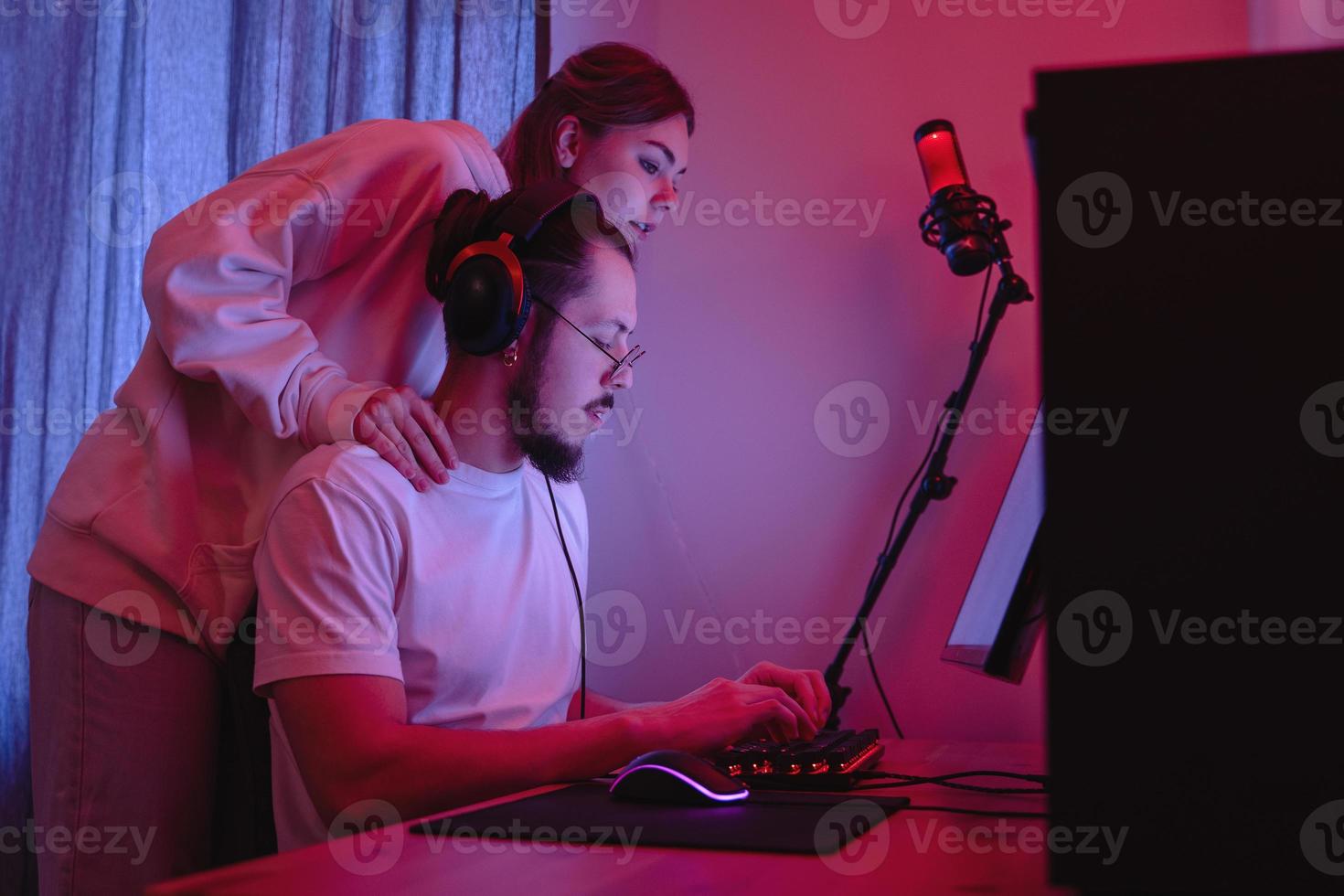 jovem casal na sala com luz neon está usando computador pessoal moderno foto