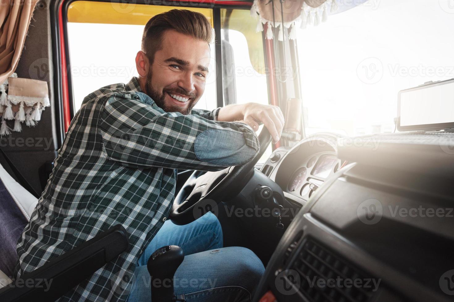 motorista de caminhão sorridente jovem e feliz dentro de seu veículo foto
