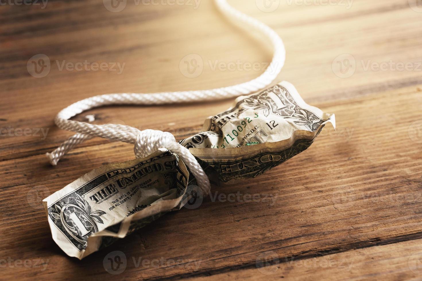 corda branca enrolada em uma nota de um dólar amassada. foto