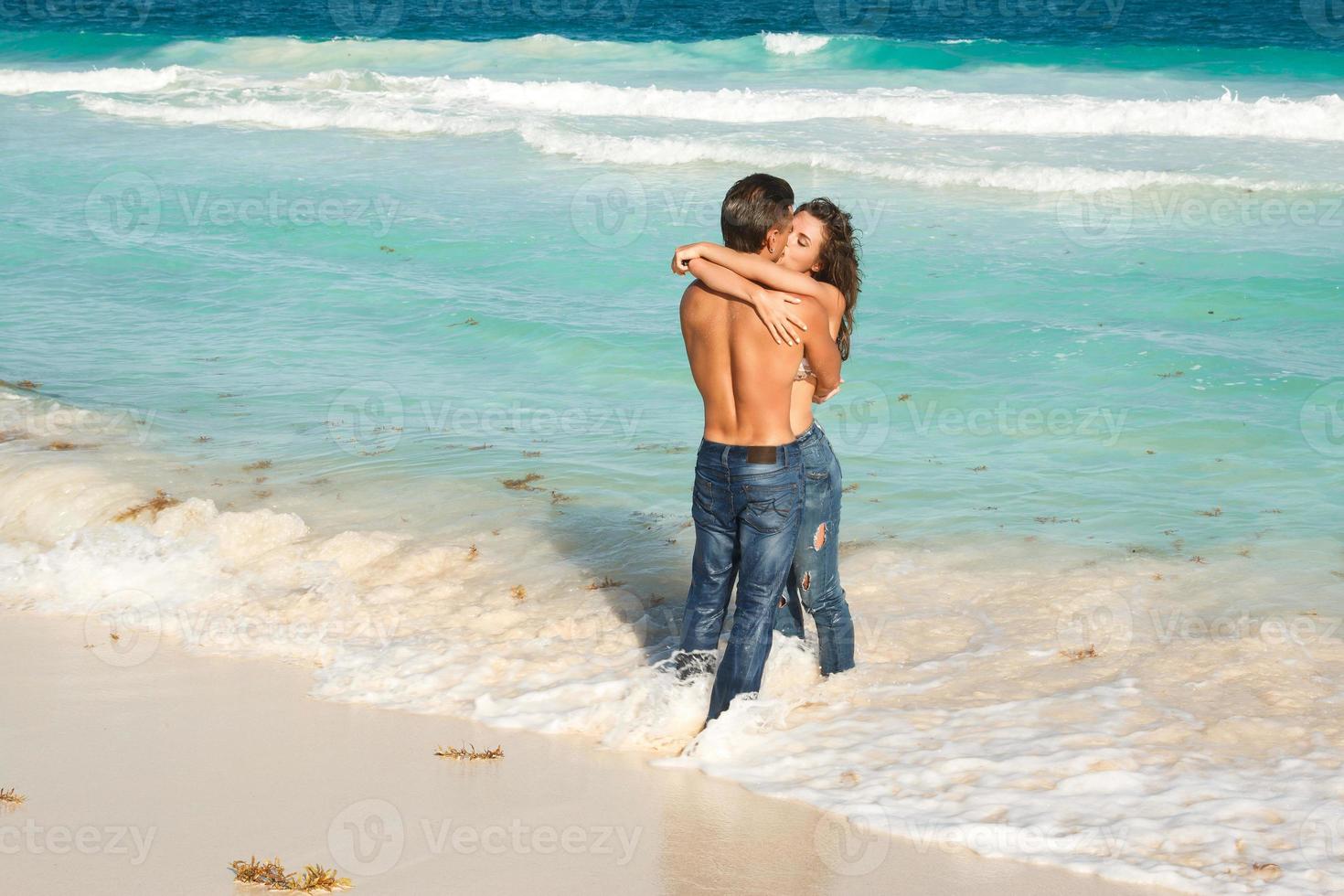 lindo casal vestindo jeans na praia tropical foto