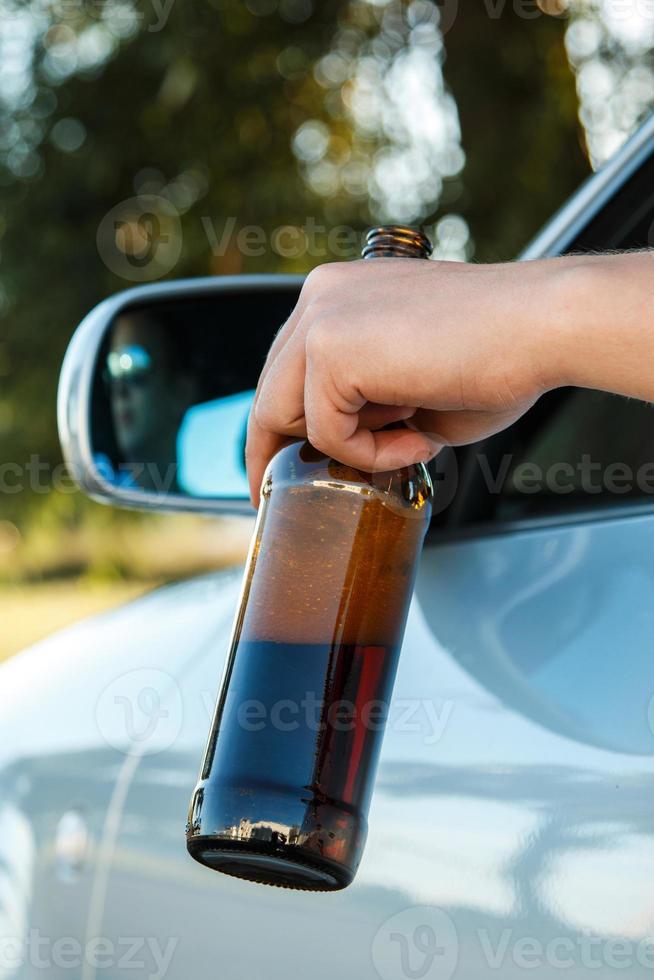 motorista de carro segurando uma garrafa de cerveja foto