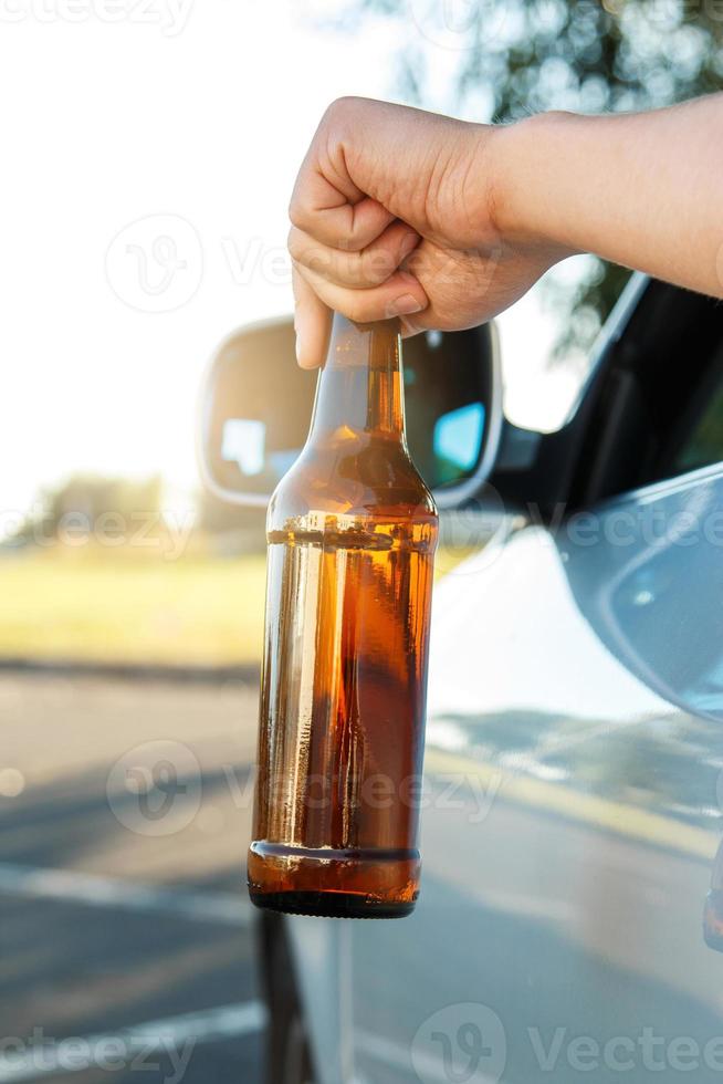 motorista de carro segurando uma garrafa de cerveja foto