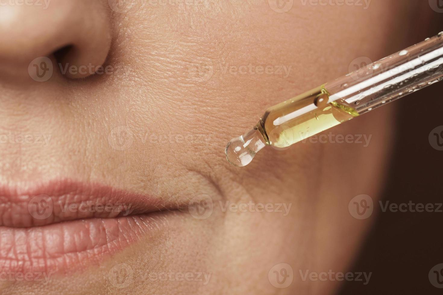 rosto feminino e conta-gotas com soro rejuvenescedor foto