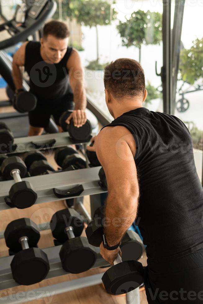 homem exercitando com halteres durante seu treino de musculação no ginásio foto