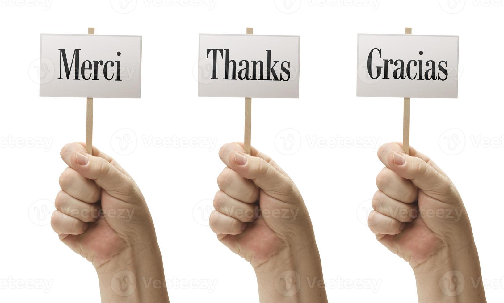 três sinais em punhos dizendo merci, obrigado e gracias foto