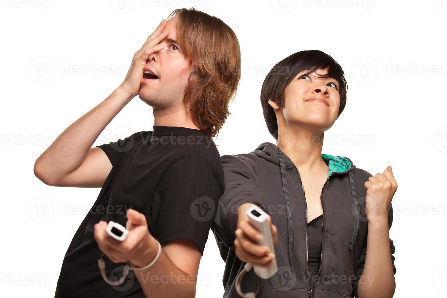 casal de raça mista jogando controles remotos de videogame em branco foto