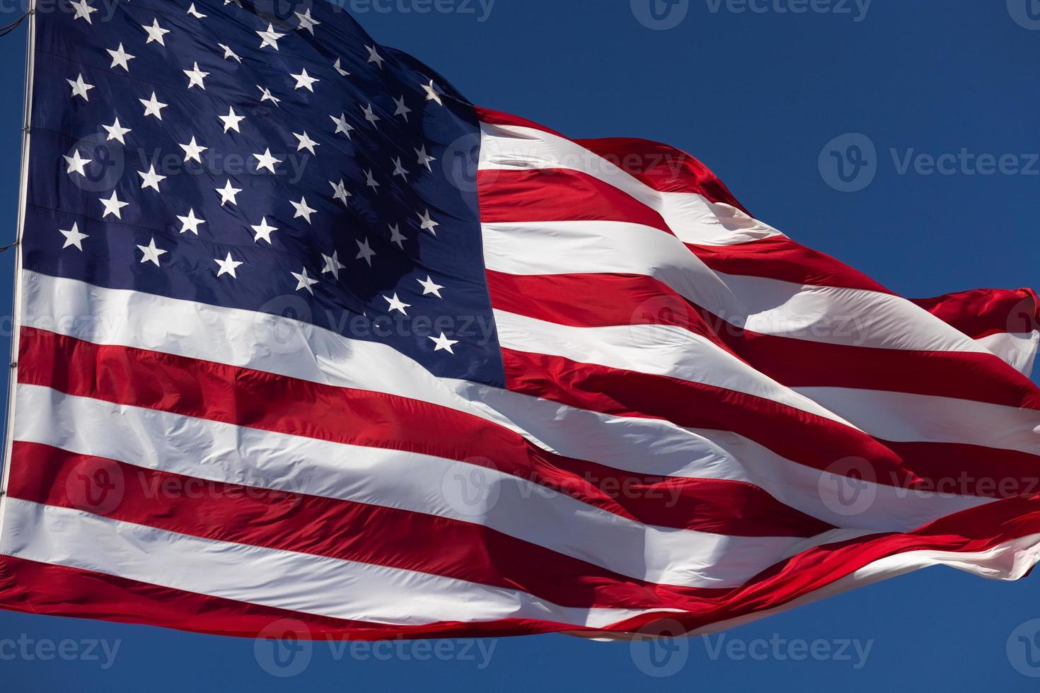 bandeira americana balançando ao vento contra um céu azul profundo foto