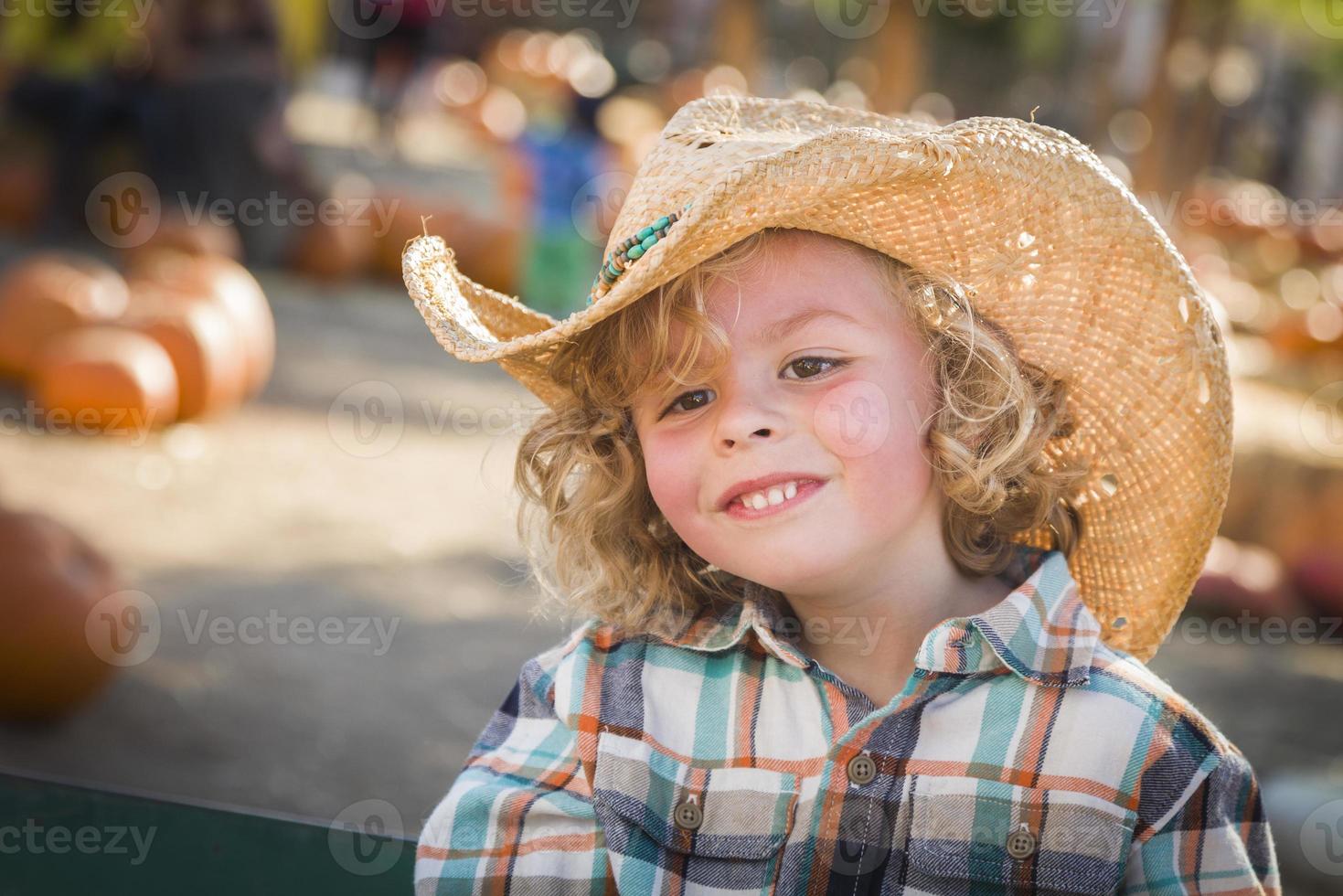 garotinho com chapéu de cowboy no canteiro de abóboras foto