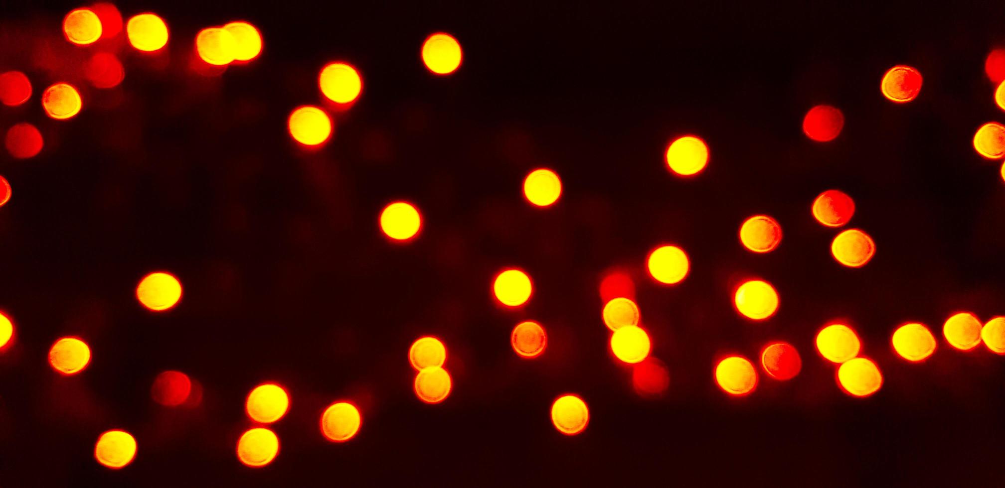 bokeh amarelo turva de luz em fundo escuro ou preto. papel de parede embaçado de iluminação. conceito de festival e celebração. foto