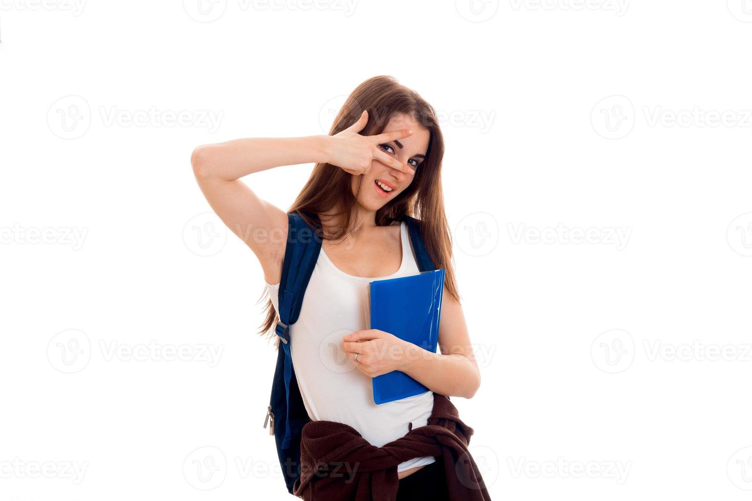 linda jovem estudante morena com mochila azul nos ombros posando isolada no fundo branco foto