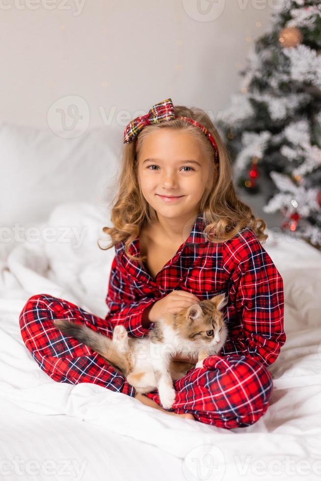 uma menina feliz recebeu um gatinho fofo de presente para o ano novo. manha de Natal. foto de alta qualidade