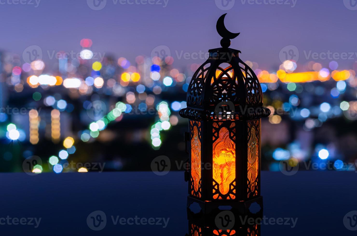 lanterna que tem o símbolo da lua no topo com fundo da cidade à noite para a festa muçulmana do mês sagrado do ramadã kareem. foto