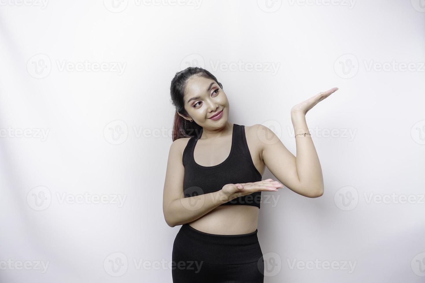 mulher esportiva asiática animada vestindo roupas esportivas apontando para o espaço da cópia em cima dela, isolado pelo fundo branco foto